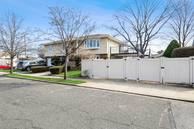 view of side of property featuring a gate, fence, and brick siding