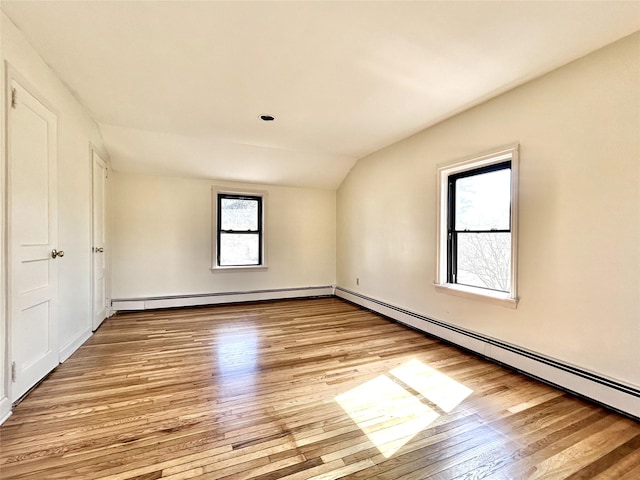 spare room with vaulted ceiling, a baseboard radiator, and light wood-style floors