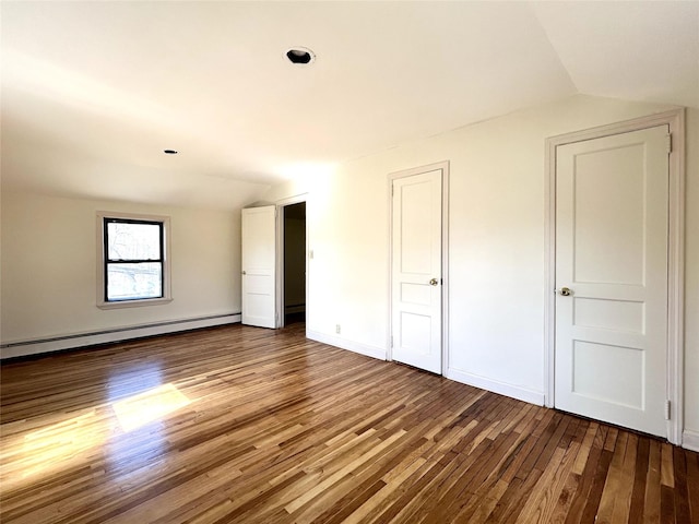 interior space featuring lofted ceiling, baseboard heating, wood finished floors, and baseboards