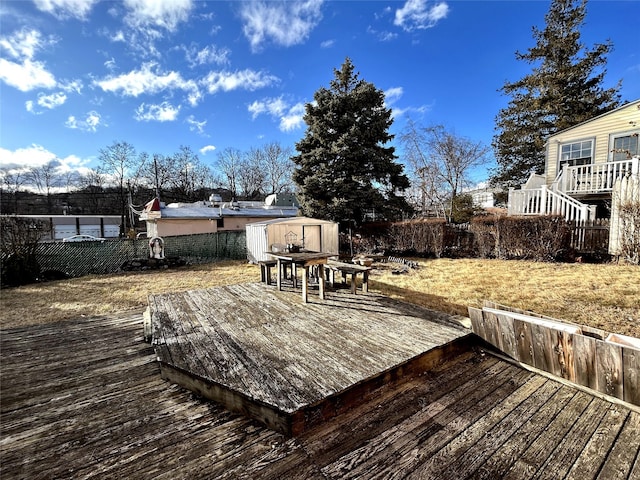 deck featuring a shed, fence, and an outbuilding