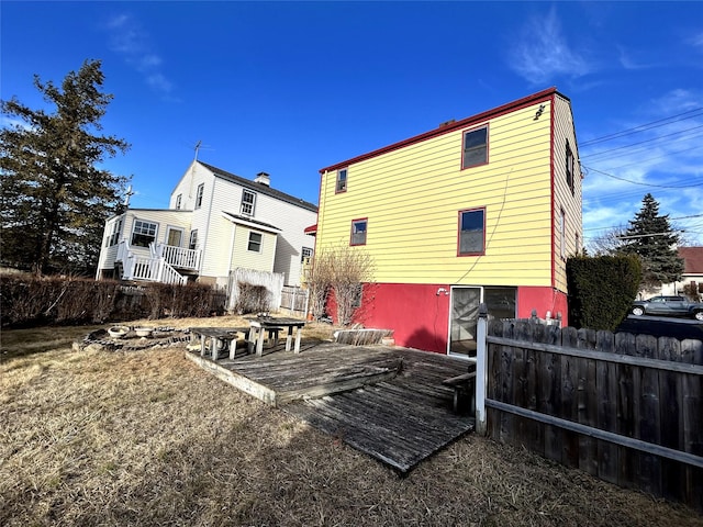 rear view of house with an outdoor fire pit and fence