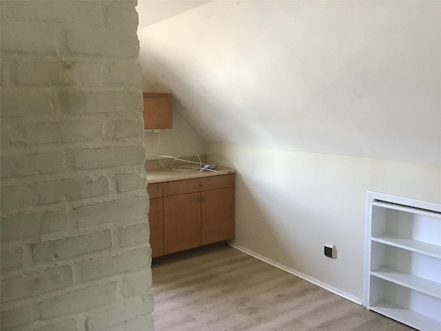 bonus room with vaulted ceiling, light wood-type flooring, and baseboards