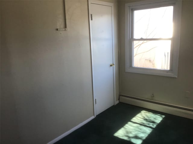 unfurnished room featuring a baseboard heating unit and baseboards