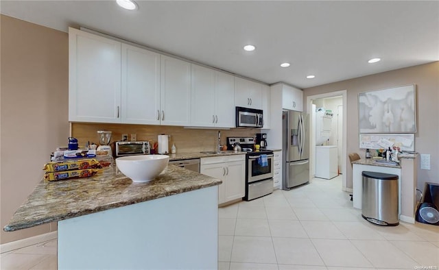 kitchen featuring decorative backsplash, white cabinets, appliances with stainless steel finishes, light stone counters, and a peninsula