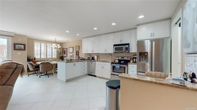 kitchen with a peninsula, white cabinets, open floor plan, appliances with stainless steel finishes, and backsplash