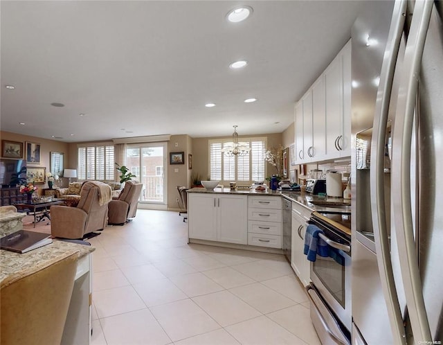 kitchen featuring stainless steel appliances, open floor plan, white cabinets, and a peninsula