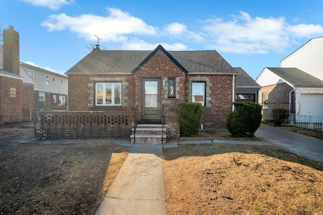 bungalow featuring fence, brick siding, and roof with shingles