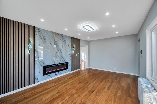 unfurnished living room featuring recessed lighting, radiator, wood finished floors, and a fireplace