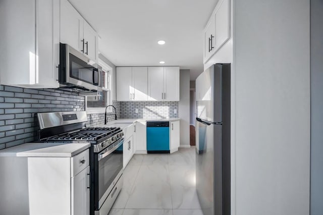 kitchen featuring tasteful backsplash, light countertops, appliances with stainless steel finishes, white cabinets, and marble finish floor