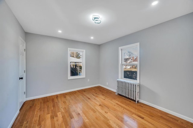 unfurnished room with recessed lighting, baseboards, radiator, and light wood-style flooring