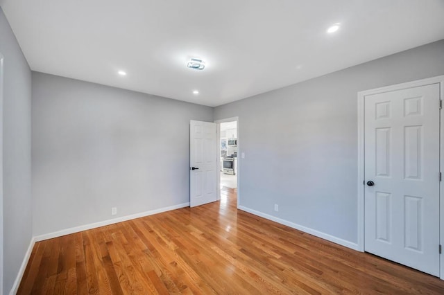 spare room featuring recessed lighting, wood finished floors, and baseboards