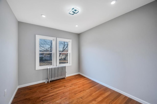 spare room with recessed lighting, baseboards, radiator, and light wood-style flooring