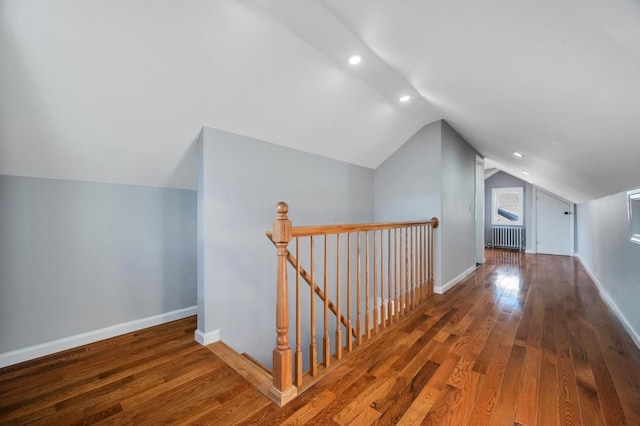 additional living space featuring vaulted ceiling, radiator, baseboards, and wood-type flooring