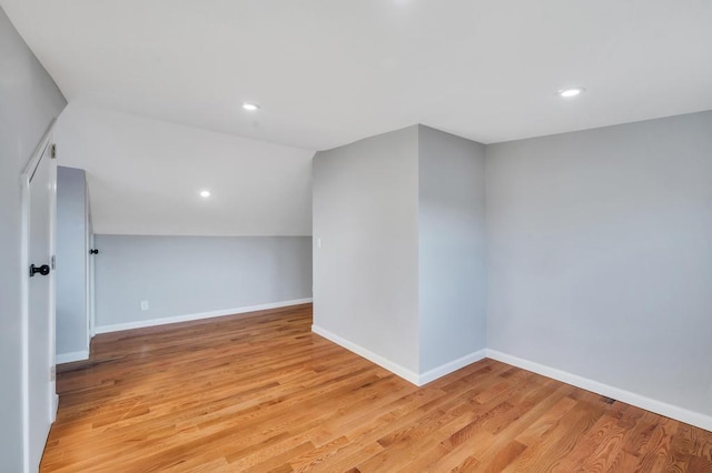 unfurnished room featuring vaulted ceiling, light wood-style flooring, recessed lighting, and baseboards