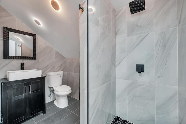 full bathroom with tile walls, toilet, lofted ceiling, a tile shower, and vanity