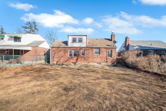 back of house featuring fence, brick siding, and a chimney