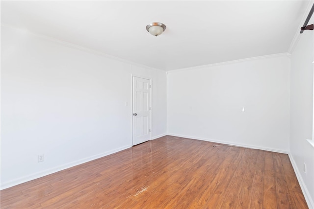 empty room featuring ornamental molding, baseboards, and wood finished floors