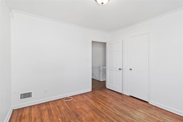 unfurnished bedroom with a closet, visible vents, baseboards, and wood finished floors