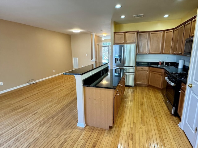 kitchen with a sink, stainless steel appliances, visible vents, and light wood finished floors