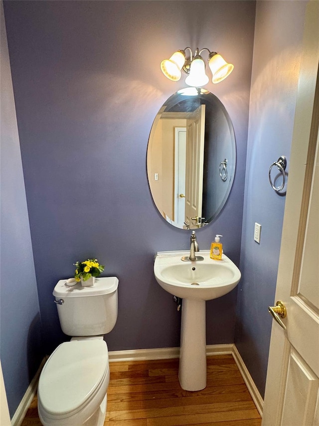 half bathroom featuring baseboards, toilet, and wood finished floors