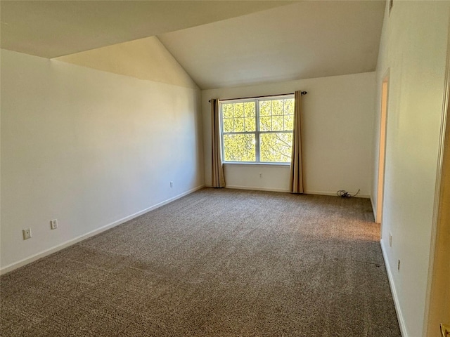 carpeted empty room with baseboards and vaulted ceiling