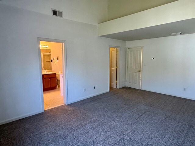 interior space with a sink, visible vents, light colored carpet, and a high ceiling