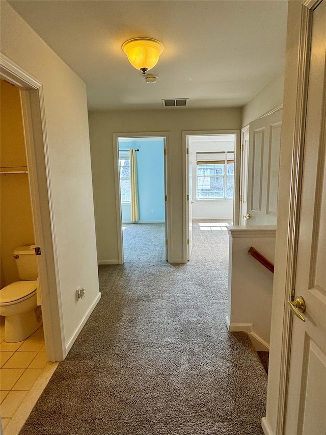 corridor featuring baseboards, visible vents, plenty of natural light, and carpet floors