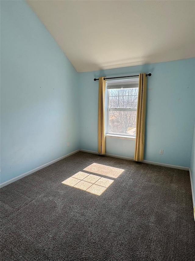 carpeted spare room with vaulted ceiling and baseboards