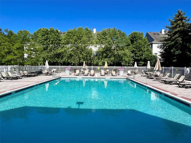 community pool with a patio area and fence