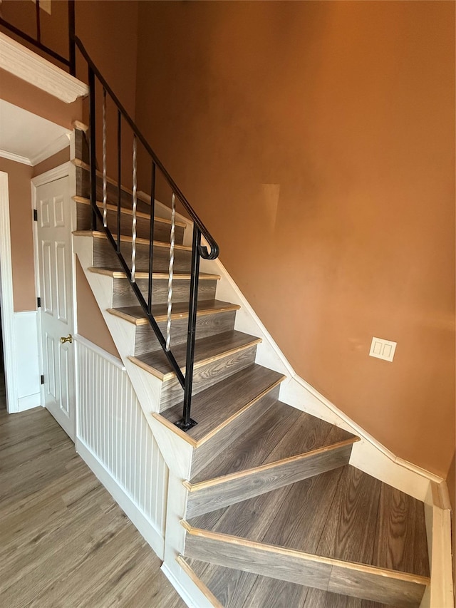 stairway featuring crown molding and wood finished floors