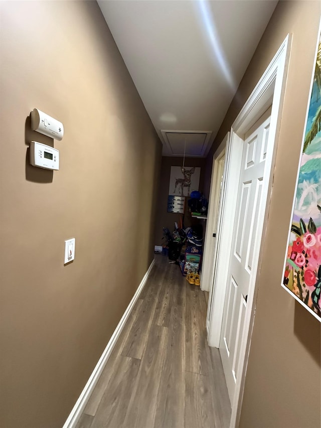 hall with attic access, baseboards, and wood finished floors