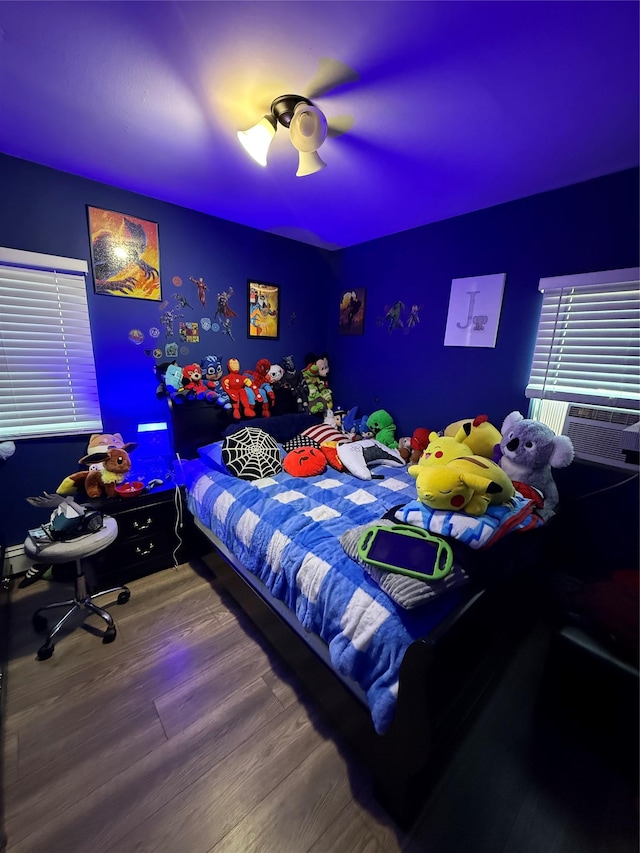 bedroom featuring a ceiling fan, cooling unit, and wood finished floors