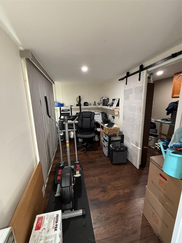 exercise room with dark wood-style flooring and a barn door