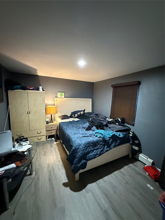 bedroom with baseboard heating and wood finished floors