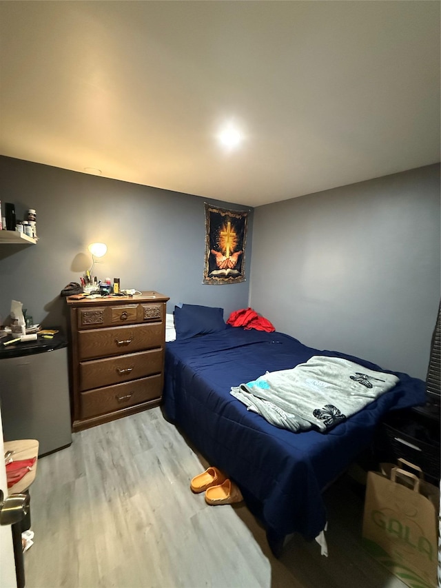 bedroom with refrigerator and light wood-style floors