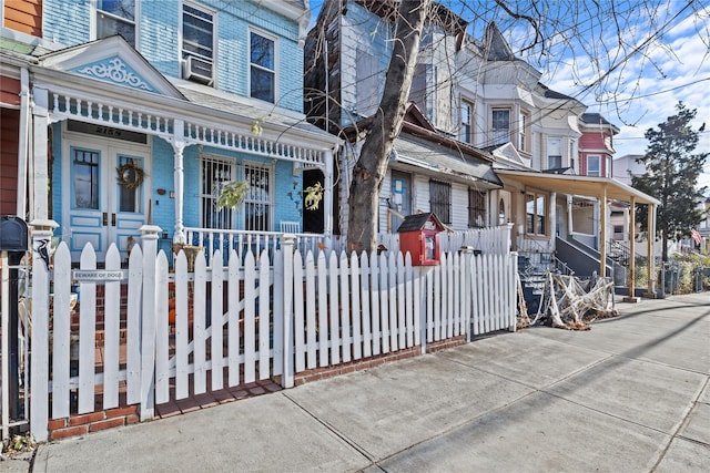 view of front of property with covered porch, a fenced front yard, and cooling unit