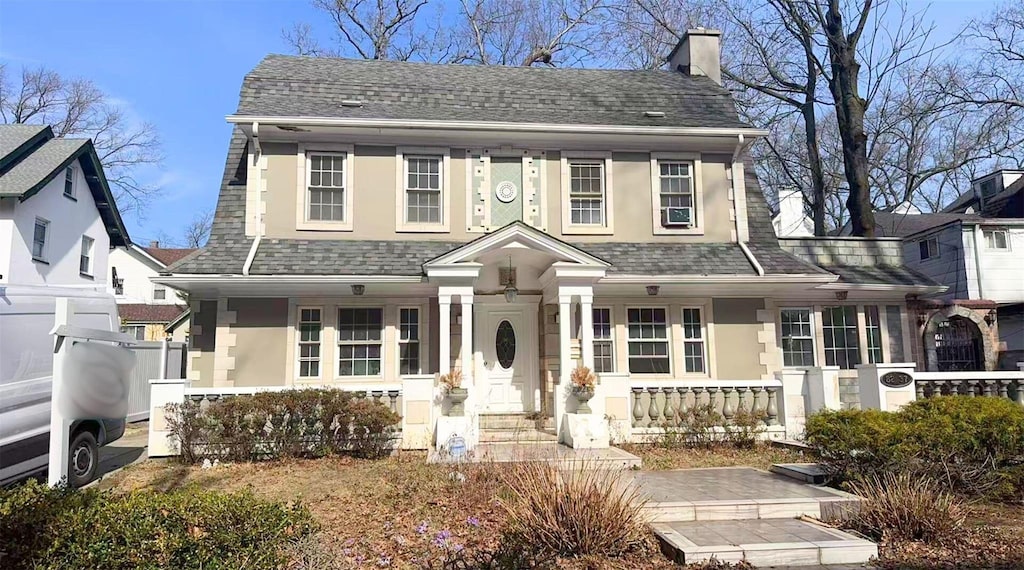 82-37 Austin St, Kew Gardens, NY 11415 - view of front of home featuring stucco siding, fence, roof with shingles, covered porch, and a chimney