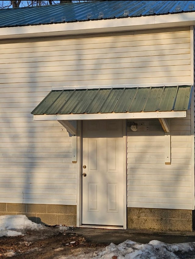 doorway to property featuring metal roof