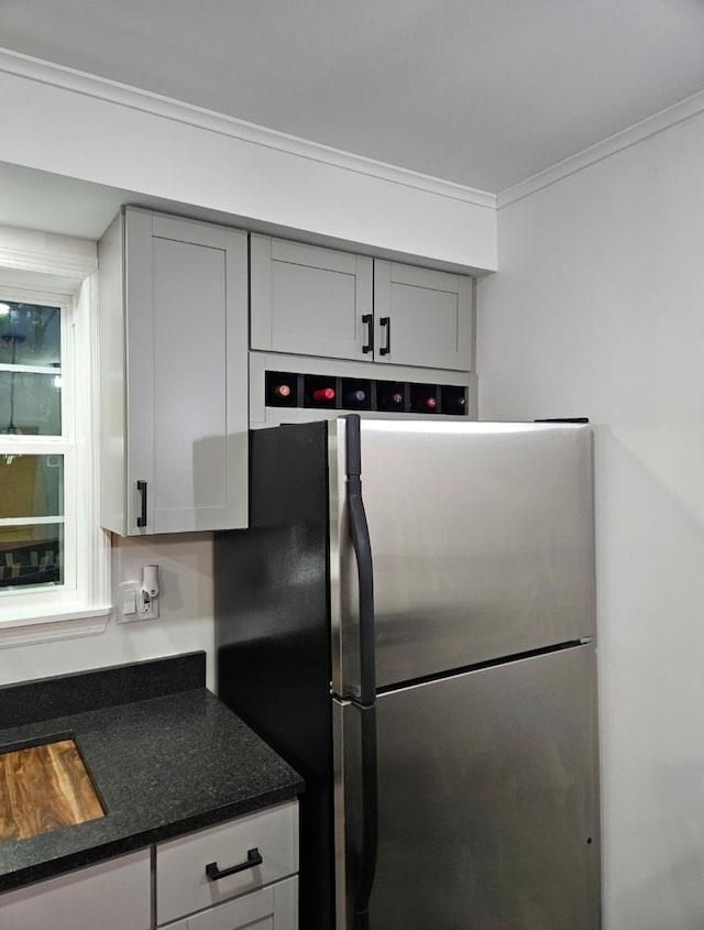 kitchen featuring dark countertops, ornamental molding, freestanding refrigerator, and gray cabinetry