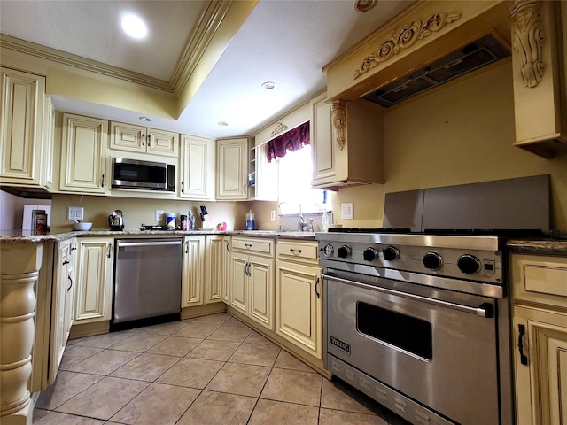 kitchen featuring ornamental molding, appliances with stainless steel finishes, cream cabinets, and a raised ceiling