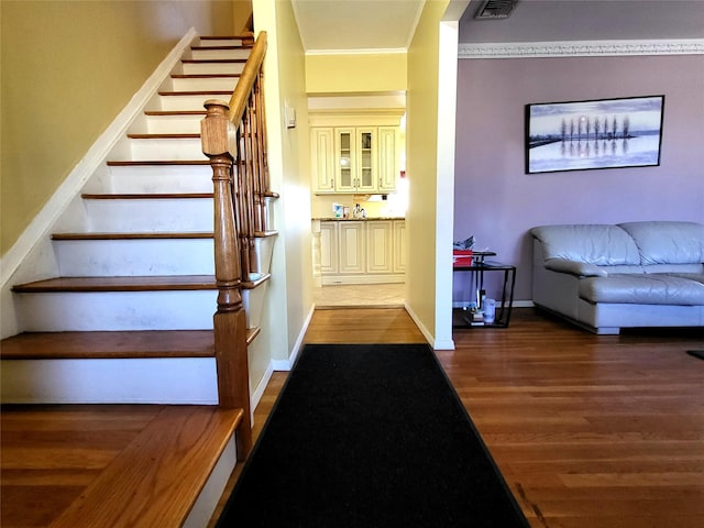 interior space featuring ornamental molding, visible vents, baseboards, and wood finished floors