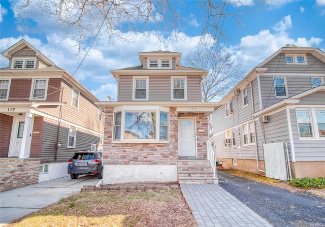 traditional style home featuring stone siding, driveway, and an AC wall unit