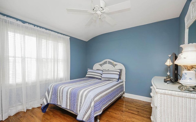 bedroom featuring a ceiling fan, vaulted ceiling, baseboards, and wood finished floors