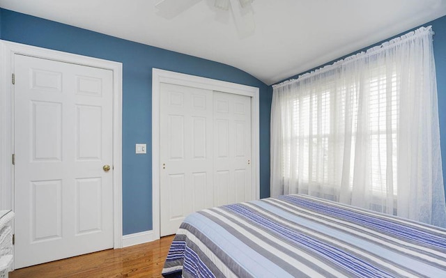 bedroom with wood finished floors, a ceiling fan, baseboards, vaulted ceiling, and a closet