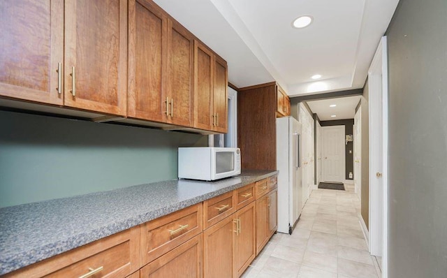 kitchen featuring light tile patterned floors, white appliances, brown cabinetry, and recessed lighting