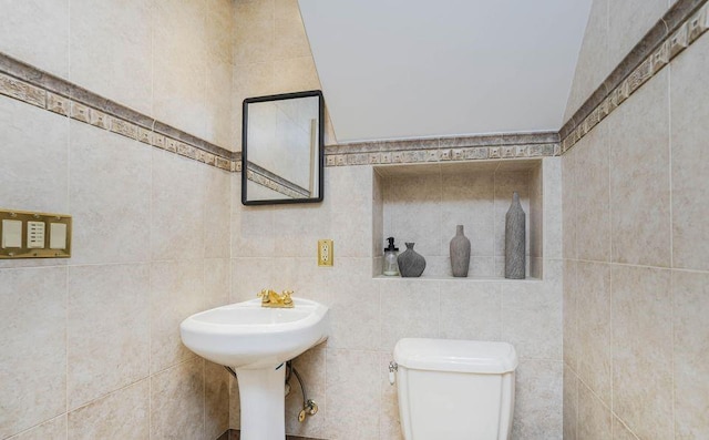 bathroom with toilet and tile walls