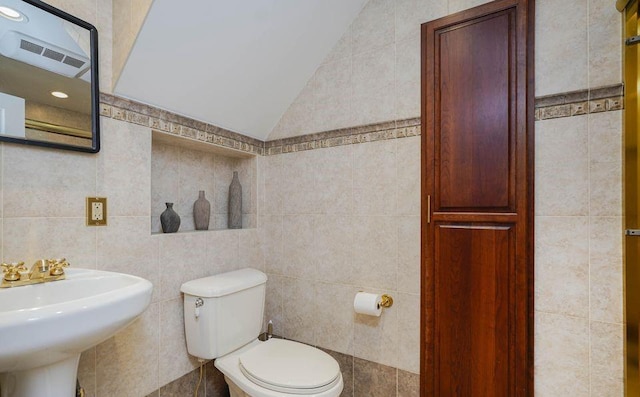 half bath with toilet, visible vents, and tile walls