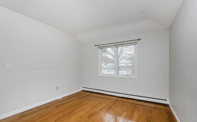 spare room with lofted ceiling, hardwood / wood-style floors, a baseboard radiator, and baseboards