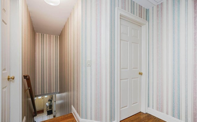 hallway featuring wood finished floors and wallpapered walls