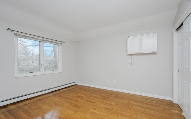 spare room with baseboards, baseboard heating, and light wood-style floors